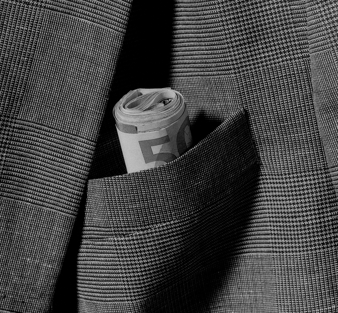 Close up of a suit and cash rolled up in the bag.r Tasche ist Bargeld eingerollt.