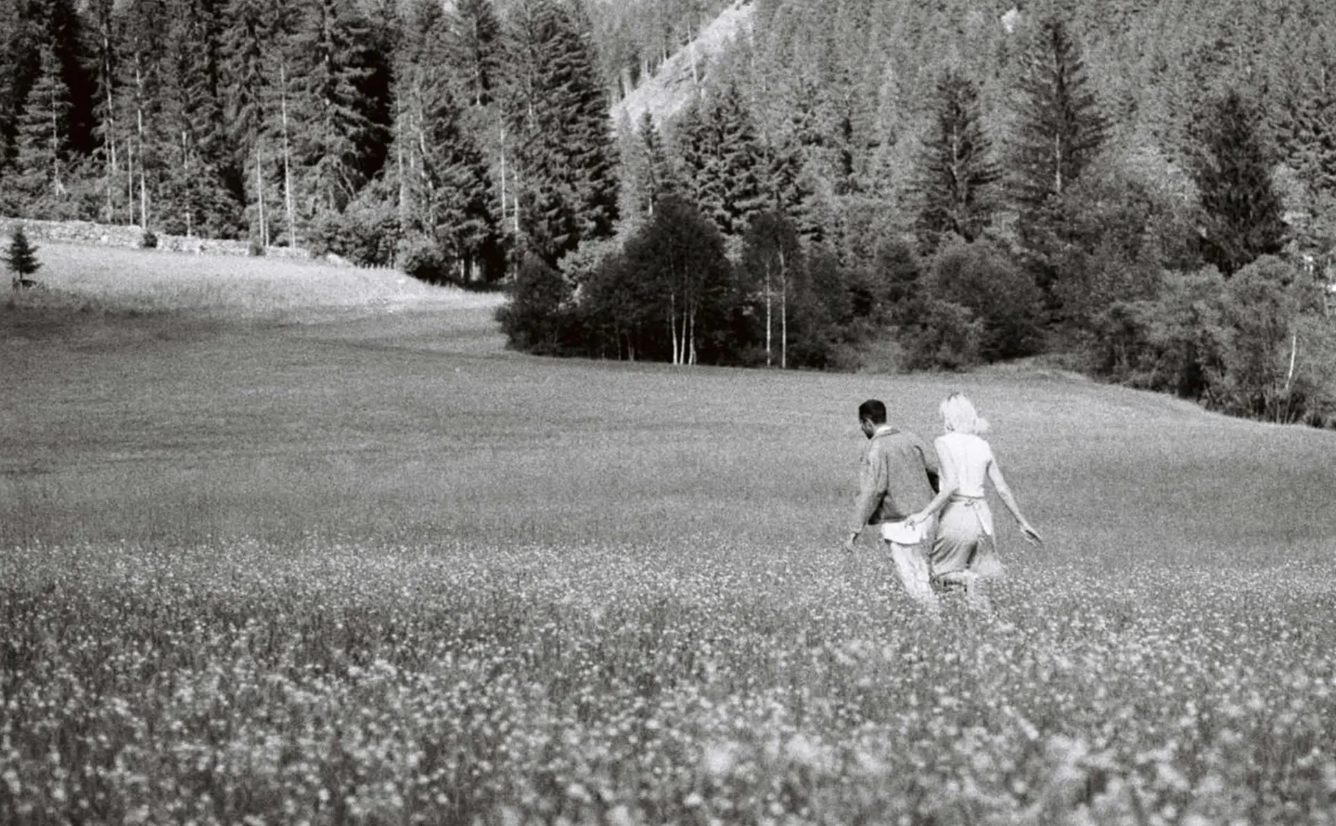 Couple strolling across a field. Picture is only in black and white.