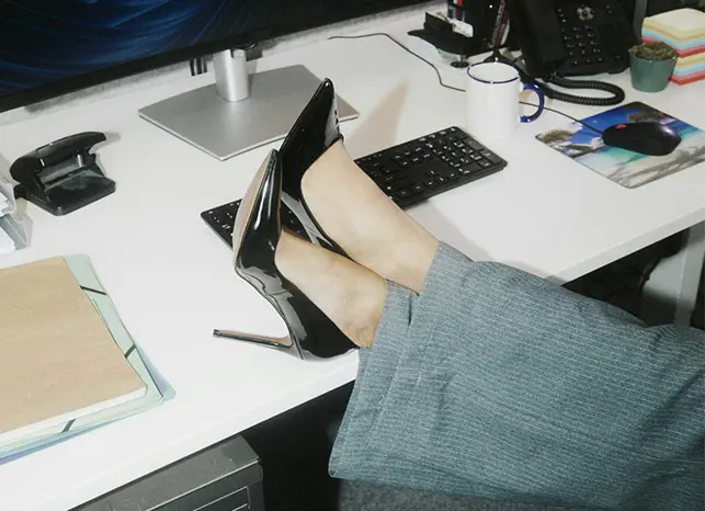 Businesswoman has her feet on the table and wears high heels.