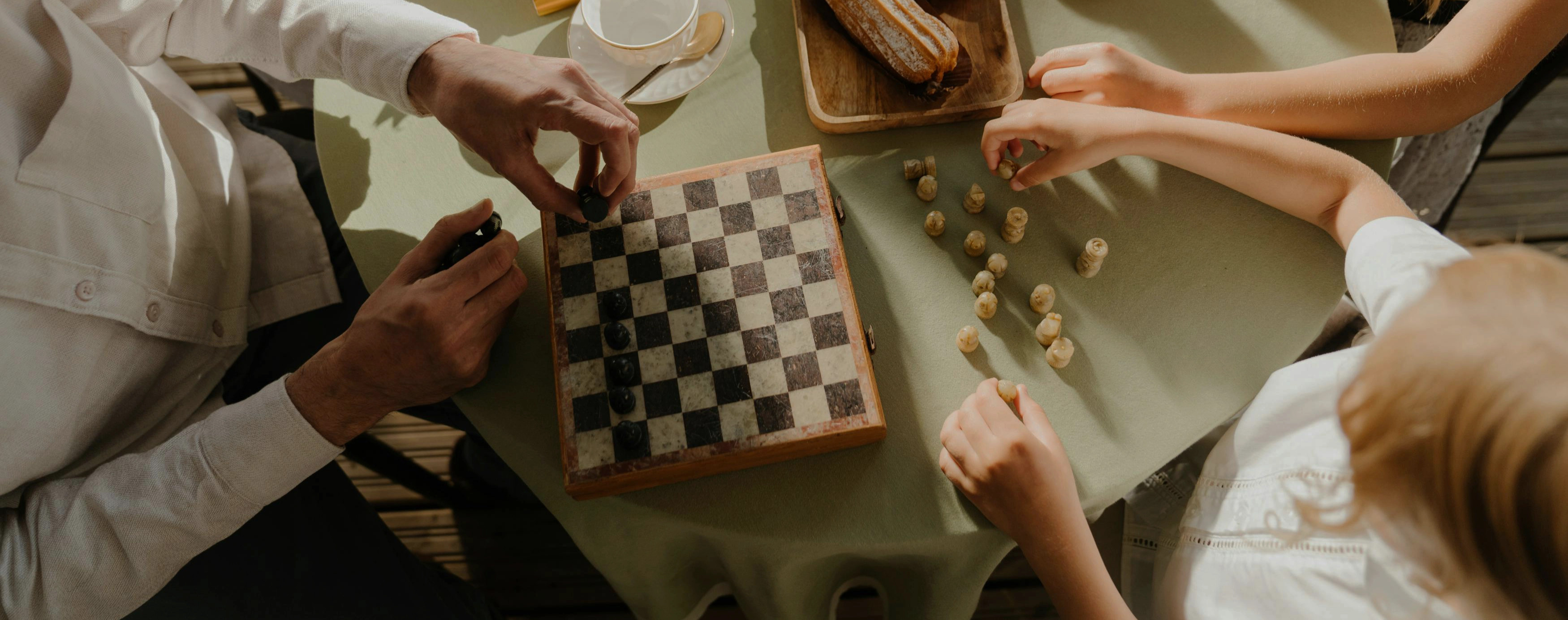 Family playing chess and eating cake.