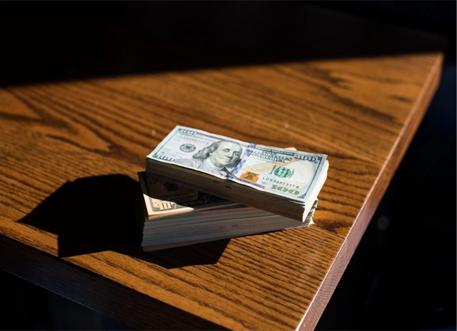 Gestapelte Dollar Scheine auf einem Holztisch