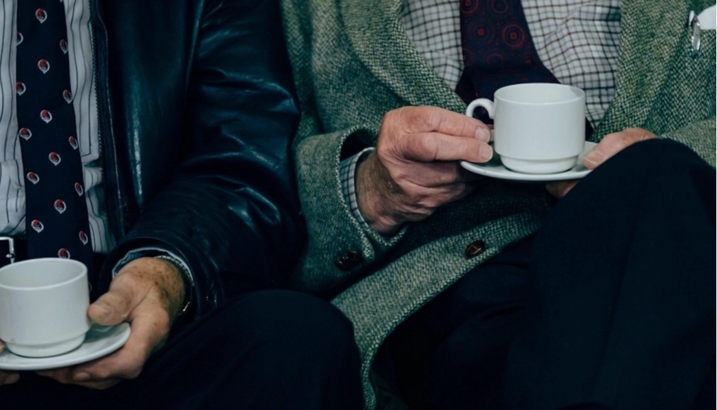 Zwei ältere Männer in Anzügen trinken Kaffee